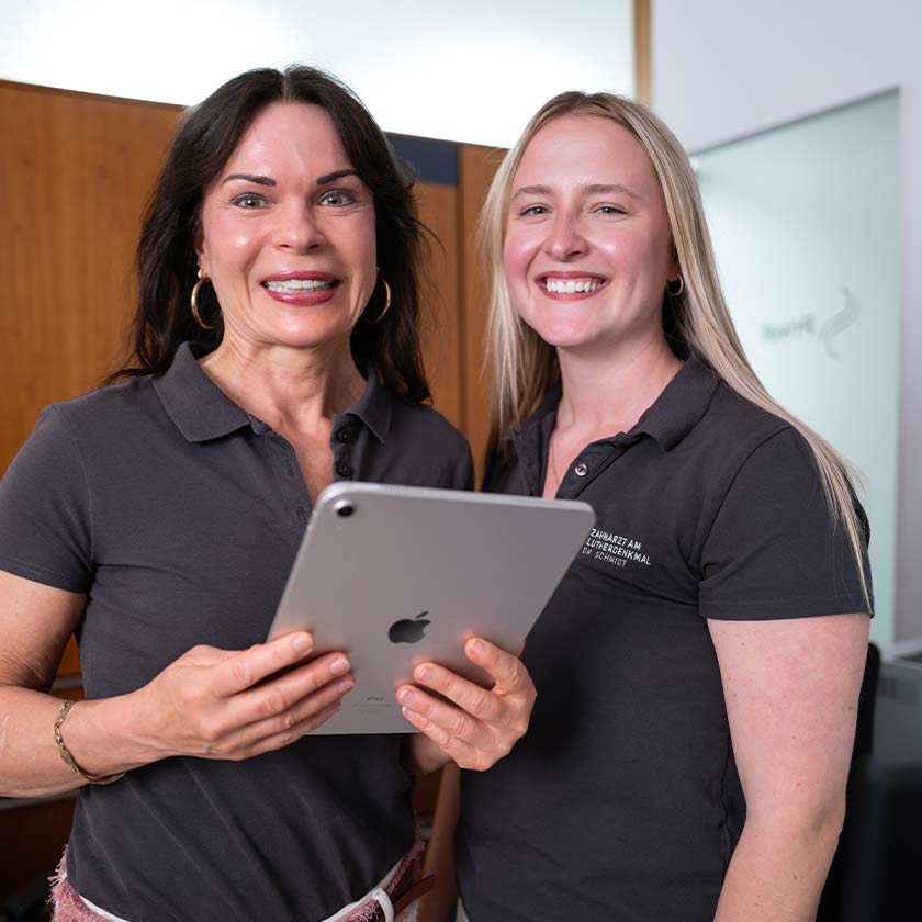 2 Mitarbeiterinnen im Emfpangsbereich der Praxis mit einem ipad in der Hand. 
