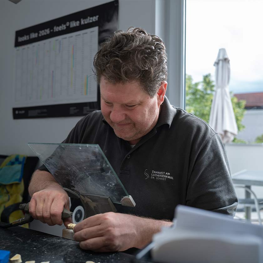 Zahntechniker im praxiseigenen Dentallabor bei der Herstellung von Zahnersatz. 