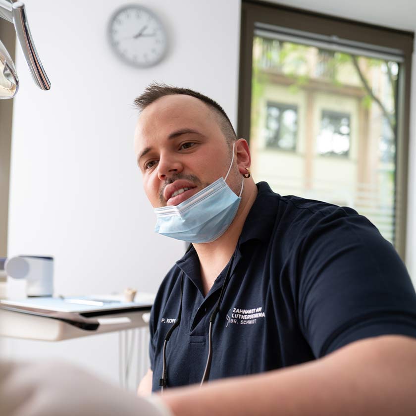 Zahnarzt Philipp Köpf im Behandlungszimmer sitzend im Gespräch mit Patienten