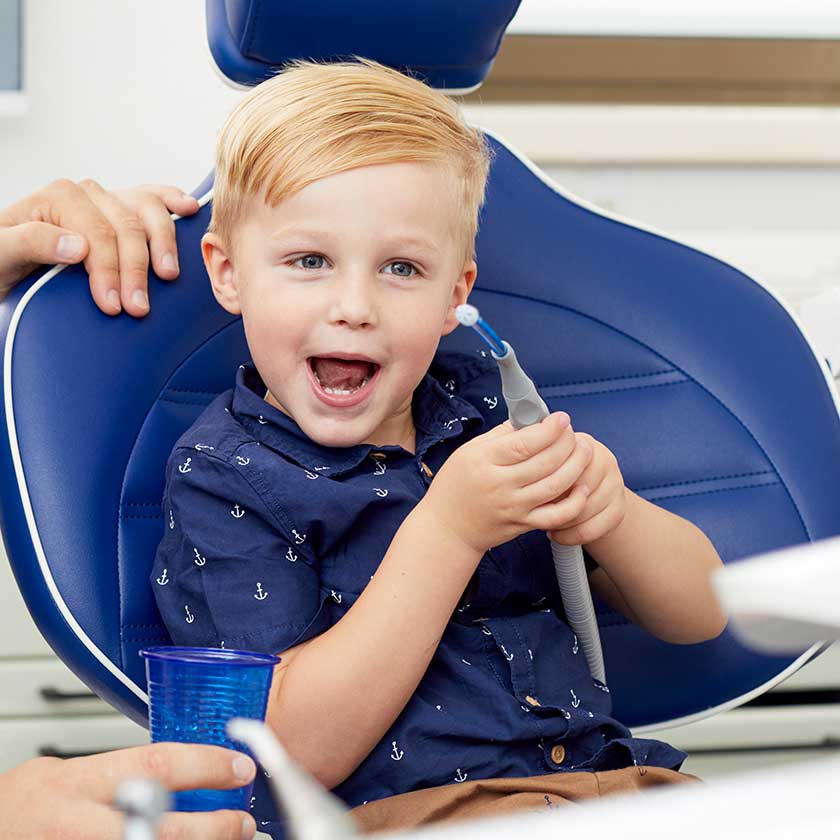 Lächelndes Kind im Behandlungsstuhl während eines Vorsorgetermins