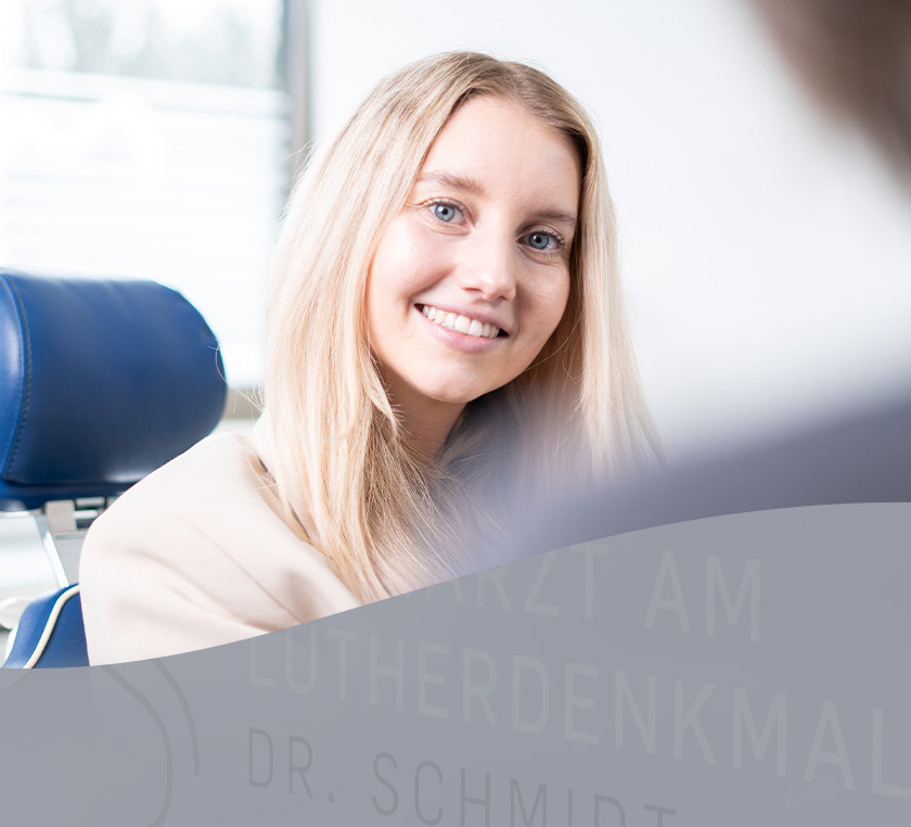 Lächelnde Patientin sitzt auf dem Behandlungsstuhl in der Praxis Dr. Schmidt in Worms
